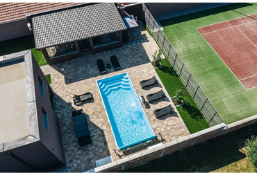 Blå rektangulär glasfiberpool Aruba med kaklade kanter och vattenrullningar