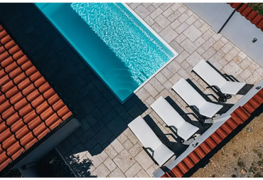 Glasfiberpool Saba med turkost vatten och vita kaklade kanter