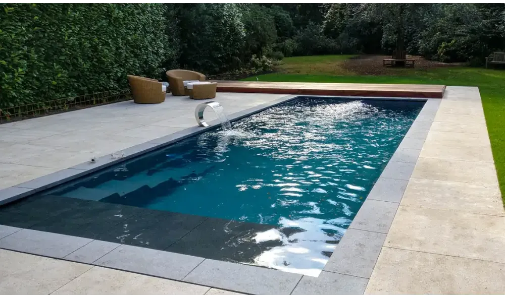 Modern Leisurepools Cube utomhuspool med djupblått vatten och grå stenplattor