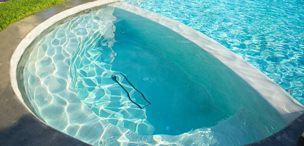 Elegant ingroundpool med kurvig form, turkost vatten och vit kant.