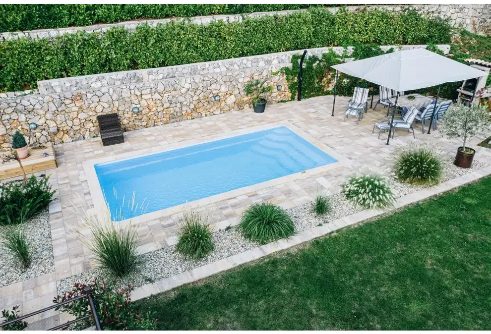 Rektangulär glasfiberpool Aruba med klar blå vatten och glasräcke