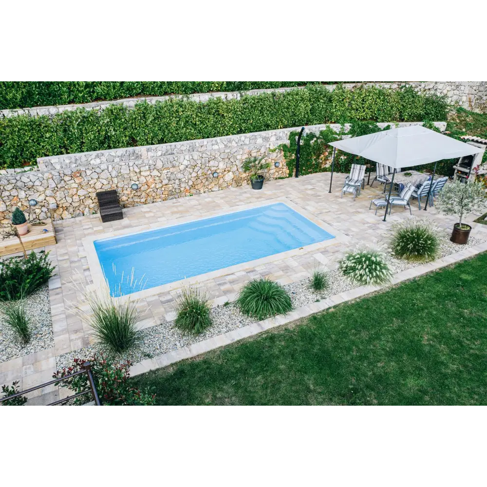 Aruba Plus trädgårdspool med rektangulär form, klarblått vatten och stenplattor