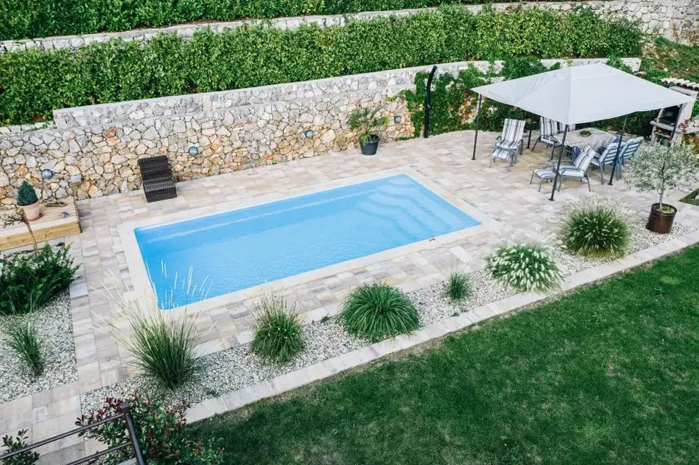 Rektangulär glasfiberpool Aruba Plus med klart blått vatten och grön kant