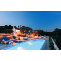 Blåvita loungestolar vid lysande Haiti trädgårdspool med avrundad trappa vid skymning