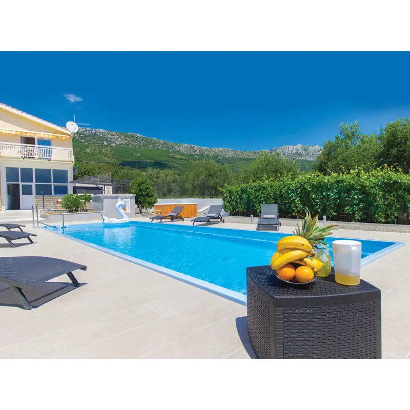 Svart rottingbord med bananer, apelsiner och gul vätska vid Glasfiberpool Jamaika