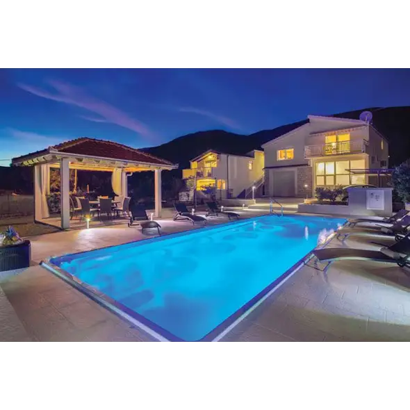 Glasfiberpool Jamaika med blåvatten och pooltak vid skymning