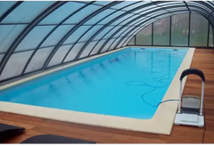 Blå inomhuspool med genomskinligt valv och trädeck för glasfiberpool Jamaika 25x3 75x1 50m