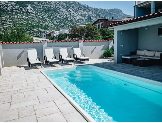 Glasfiberpool Saba med klart blått vatten och vita kaklade kanter