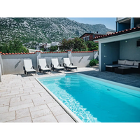 Glasfiberpool Saba 600 med klarblått vatten och vita kakelkanter