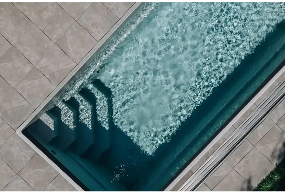Glasfiberpool Saba med klart blått vatten och vita kaklade kanter