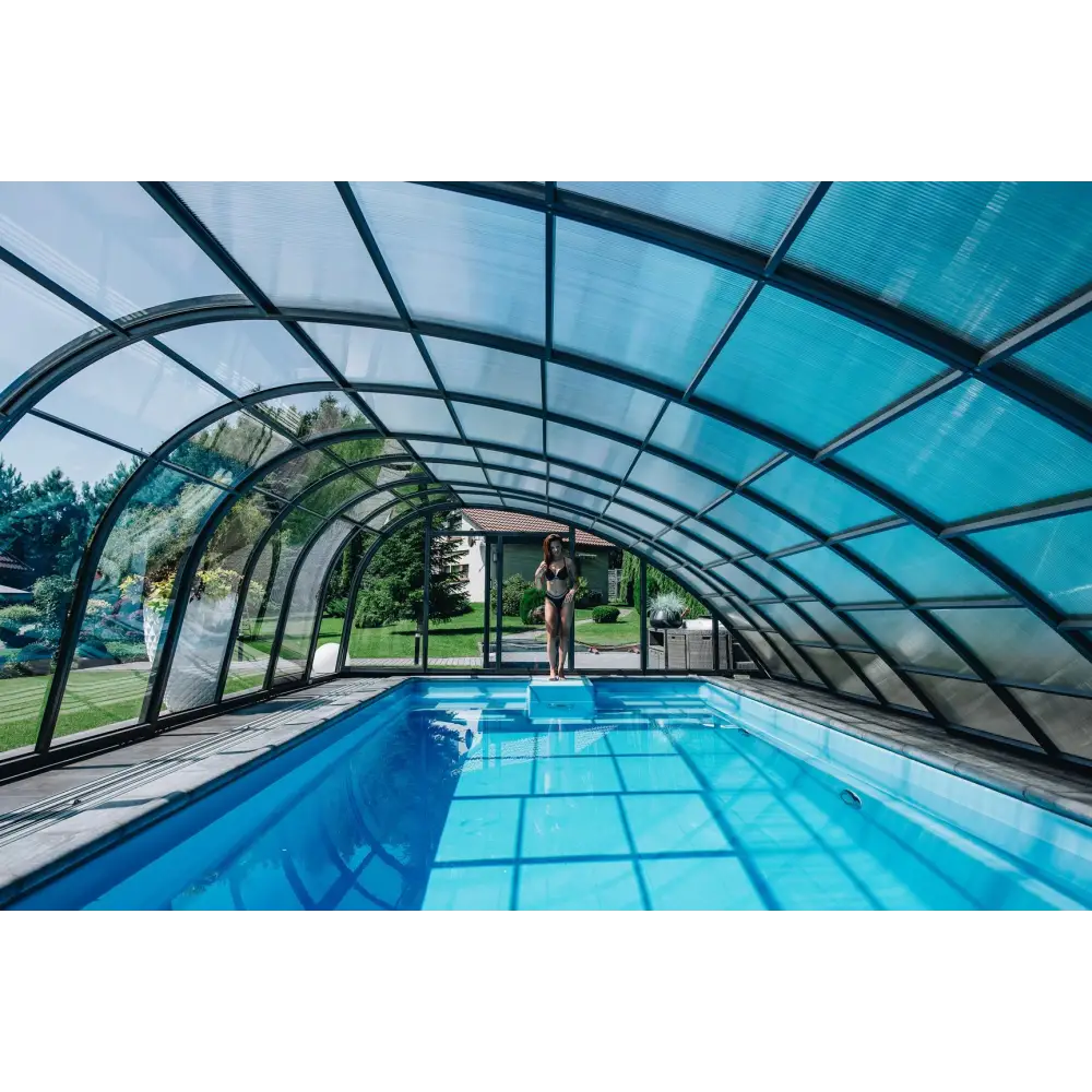 Blå inomhuspool med valvformad transparent tak och svart ramning, Glasfiberpool Trinidad 9,70m x 3,70m x 1,60m