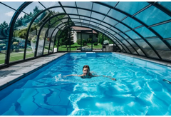 Kvinna simmar i glasfiberpool Trinidad med blå kakel och inbyggt poolöverdrag under glastak