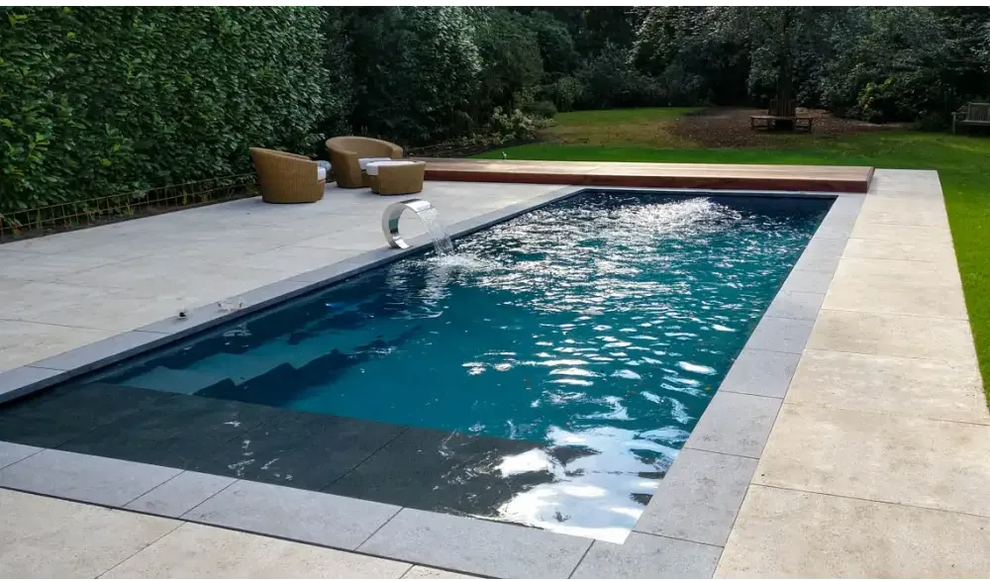 Modern Leisurepools Cube utomhuspool med djupblått vatten och grå stenplattor