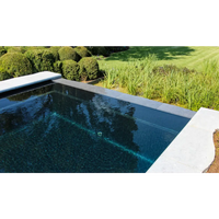 Rektangulär infinitypool Leisurepools Cube med mörkblått vatten och ljusa grå stenkanter