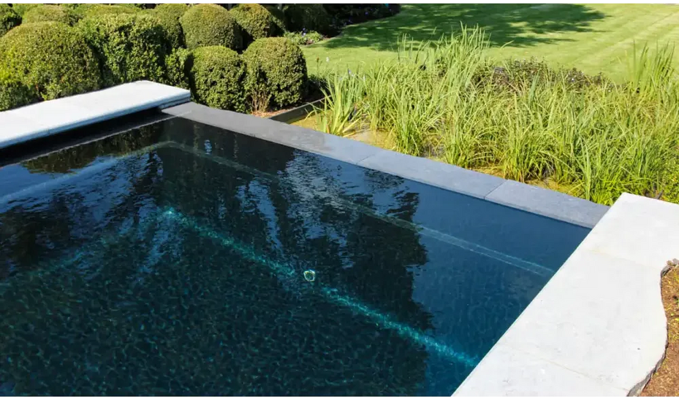 Rektangulär infinitypool Leisurepools Cube i modern design med mörkblått vatten
