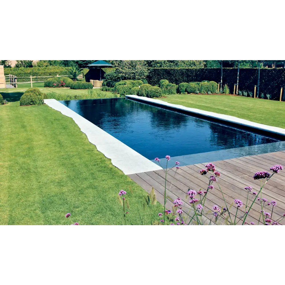 Lång rektangulär infinitypool Leisurepools Cube med mörkblått vatten och vita betongkanter