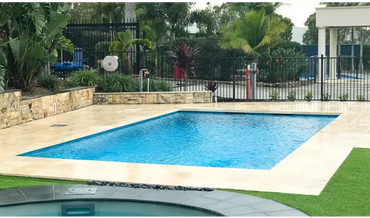 Leisurepools Elite rektangulär modern pool med klarblått vatten och beige sten