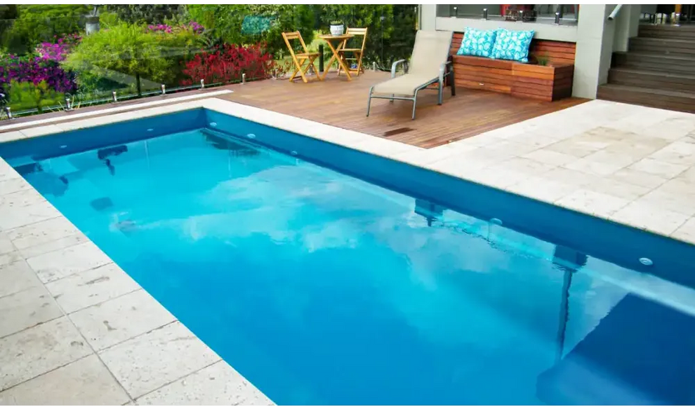 Rektangulär Leisurepools Harmony pool med klart blått vatten och stenplattor
