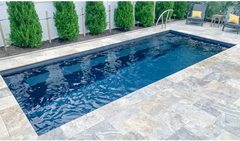 Rektangulär Leisurepools Harmony pool med klart blått vatten, grå sten och buskar
