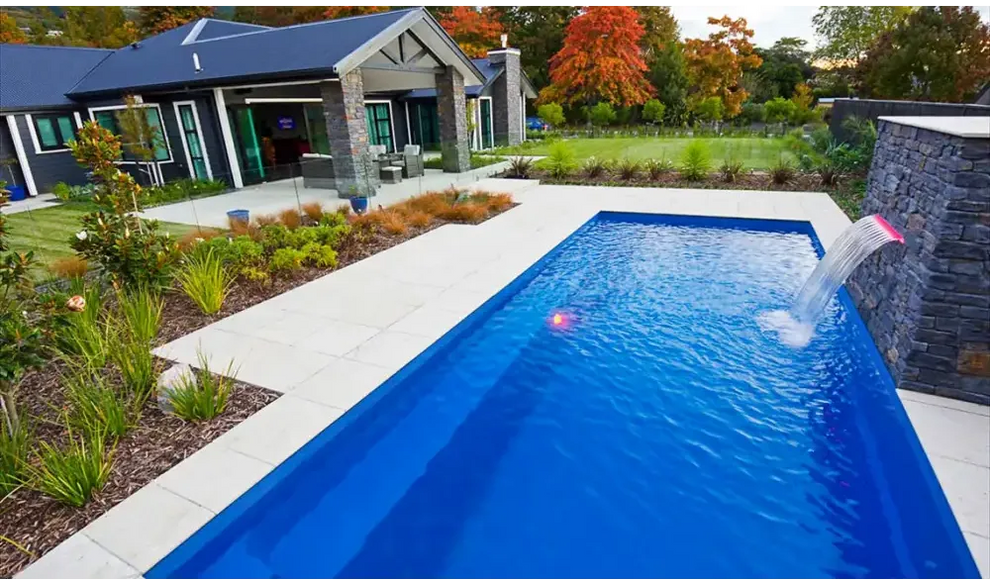 Vibrant blå rektangulär Leisurepools Harmony pool med stenfall och klart vatten