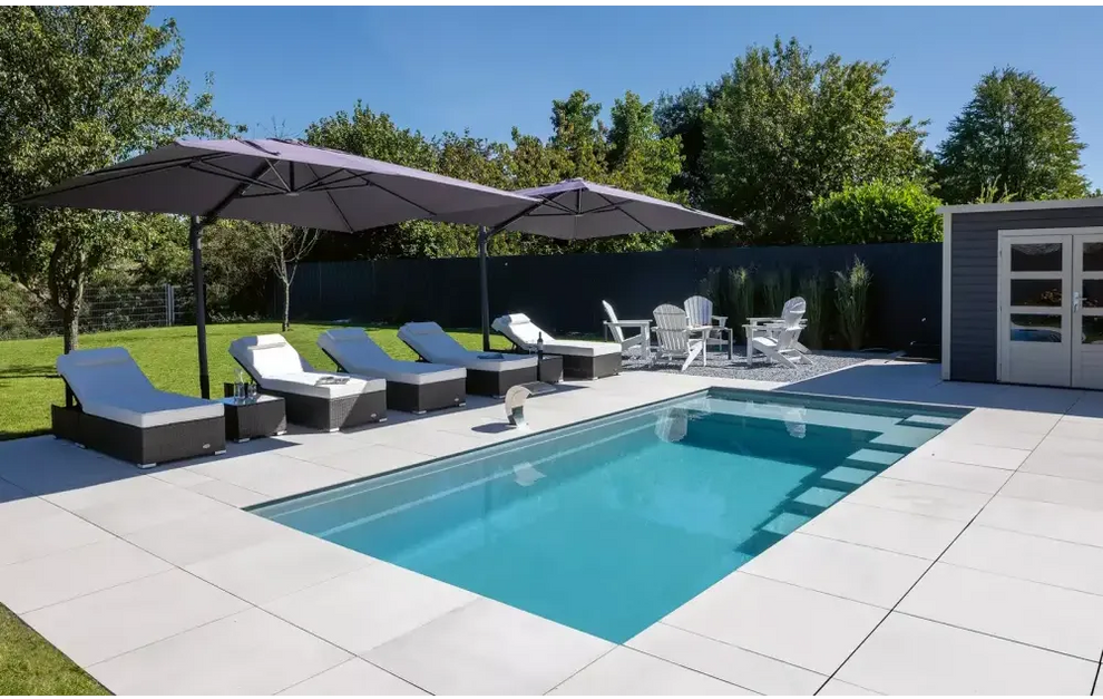 Rektangulär pool med hög vattenlinje, visuellt imponerande design och rottingloungestolar