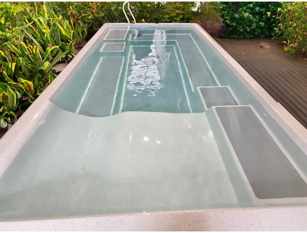 Rektangulär fiberglasspool Mira390 med ljusgrå interiör, inbyggda steg och grön omgivning för wellness pool ovanmark
