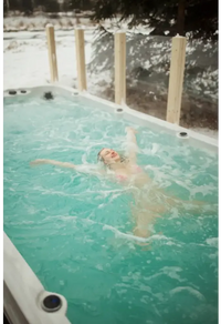 Kvinna i rosa bikini flyter lugnt i PassionSpa Activity 2 Swim Spa i snöig miljö
