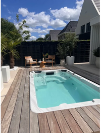 Vit PassionSpa Aquatic 1 Swim Spa – Sport Collection, vit rektangulär med turkost vatten och jetstrålar på trädeck