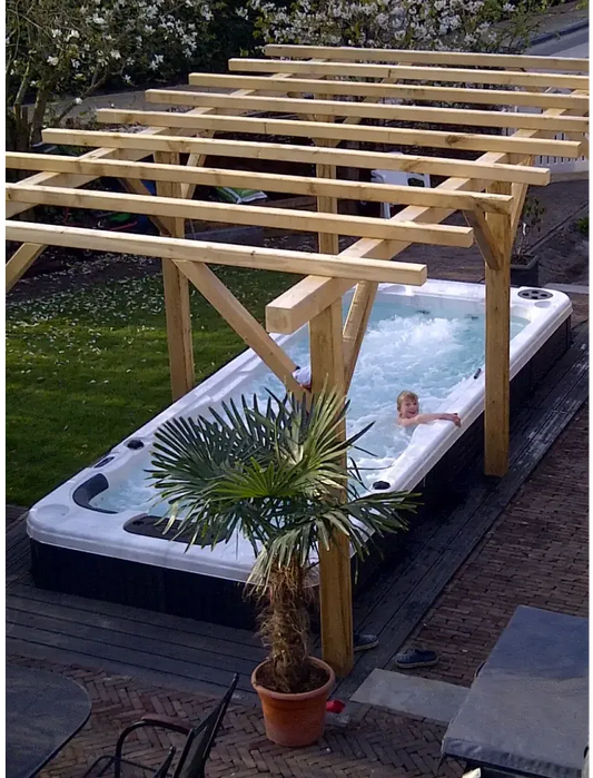 Vit och svart PassionSpa Aquatic 2 Swim Spa med bubblande vatten under pergola
