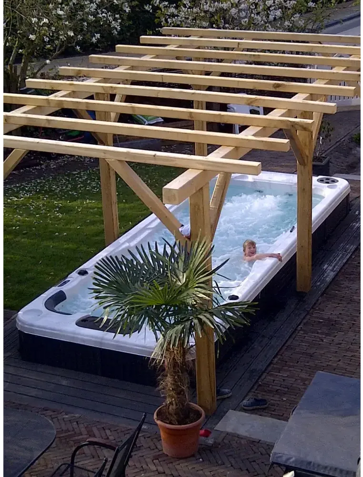 Vit och svart PassionSpa Aquatic 2 Swim Spa med bubblande vatten under pergola