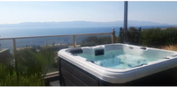 PassionSpa Refresh Spabad Pure Collection med vit och mörkgrå badtunna och glasräcke mot havet