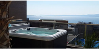 Vit och svart PassionSpa Relax Spabad Pure Collection på balkong med havsutsikt