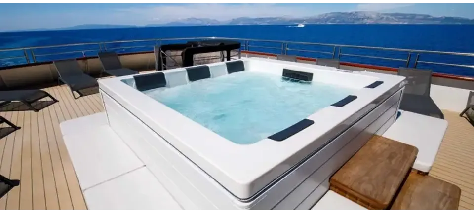 Vit PassionSpa Serene 6 Fire Pit Spabad vit rektangulär med svarta paneler och klart blått vatten på trädäck