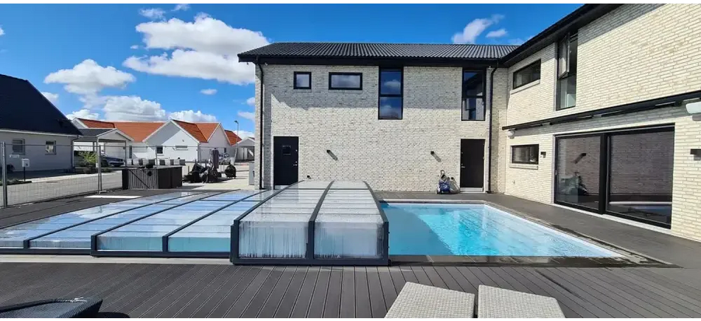 Modern vit tegelhus med svart tak, pooltaket Icon med sarg klarplast i antracit och stora glasdörrar