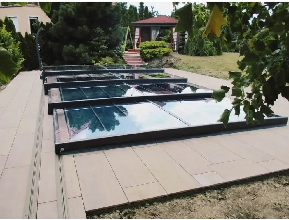 Pooltak Mästare Plus med modern glasdesign och svart ram över kaklat uteplats