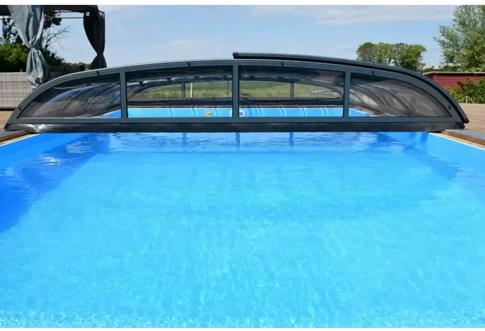 Pooltak Nivo Kit 1060B med svart bågad pooltäckning och transparenta paneler över blå pool
