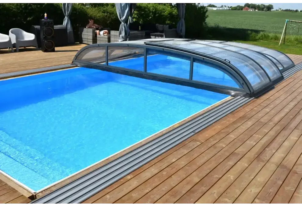 Blå inground pool med Pooltak Nivo Kit 1060B bågad täckning på trädeck