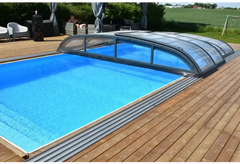 Blå inground pool med Pooltak Nivo Kit 650B transparenta paneler på trädeck. Installation finns