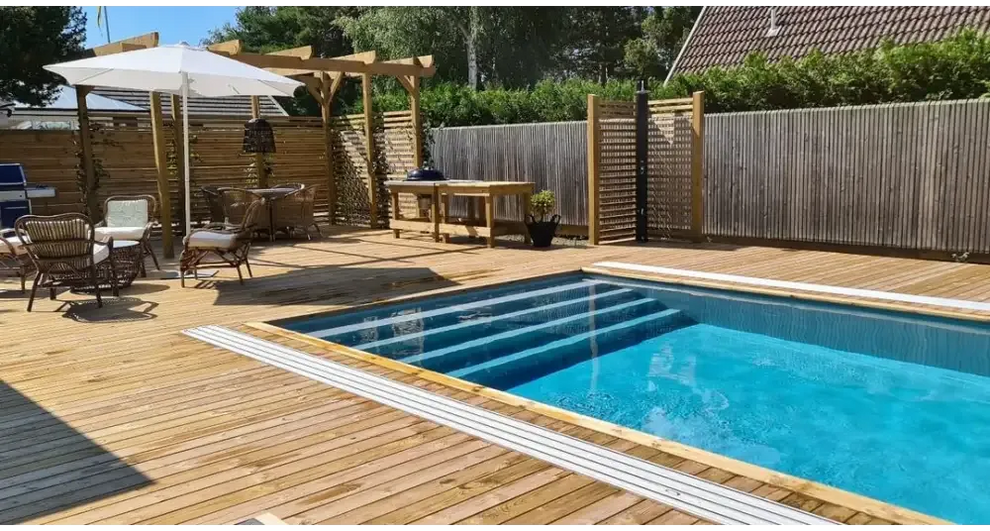 Pooltime Exklusiv 12mm rektangulär pool med klart blått vatten och vita kakelkanter i trädeck
