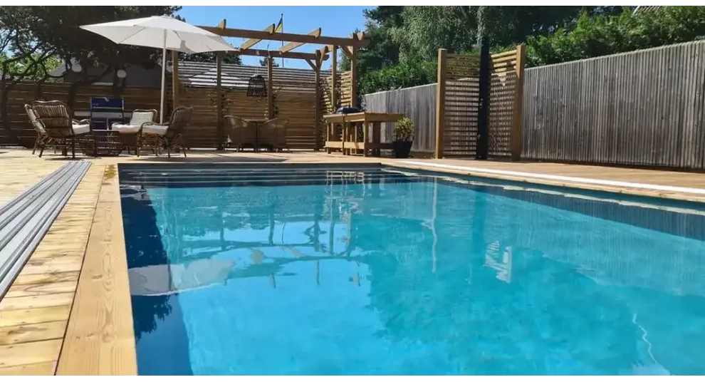 Pooltime Exklusiv rund dagbädd med böjt baldakin, rektangulär med klart blått vatten och trädeckkanter