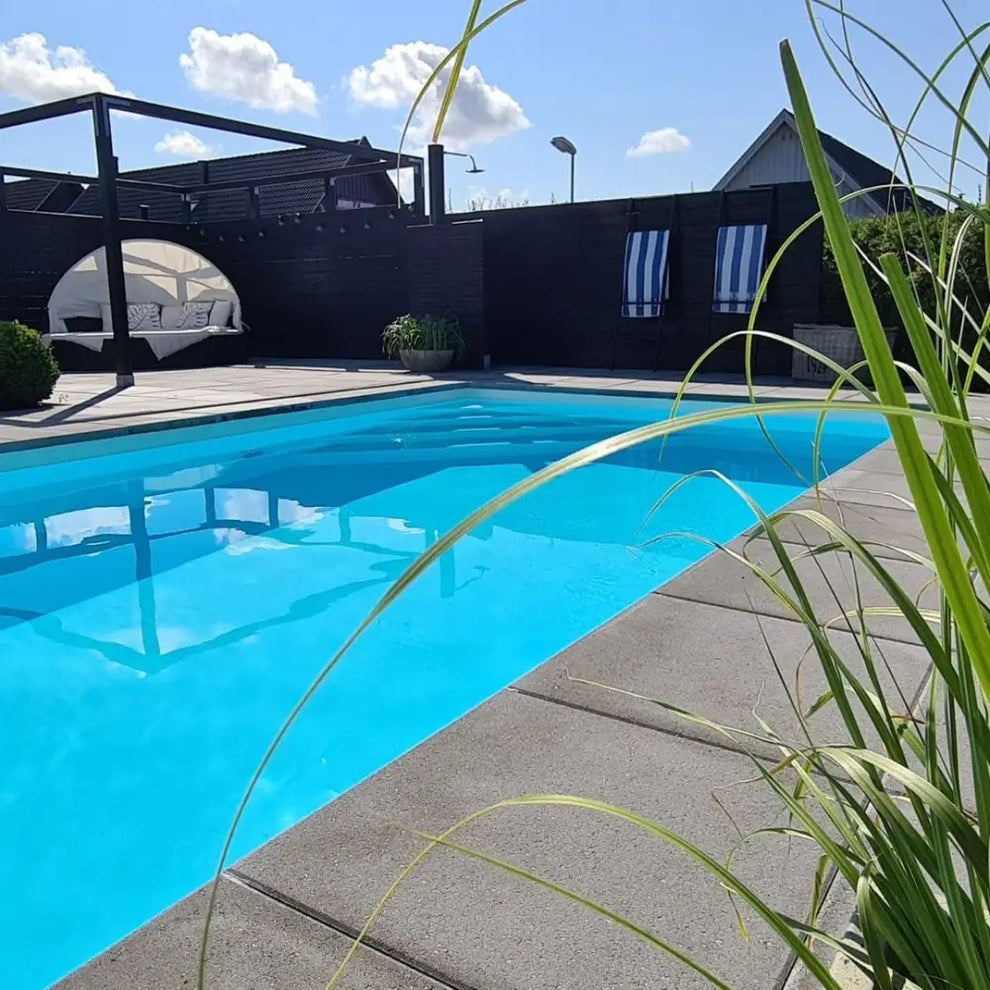 Pooltime Exklusiv vid kristallklar blå pool med gräsmatta