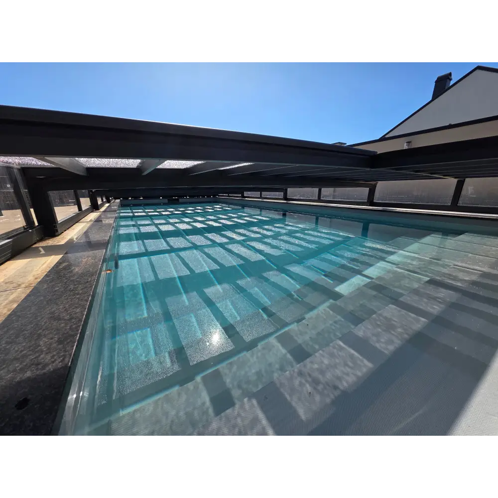 Lång rektangulär pooltime exklusiv pooltak med klar turkos vatten och svarta bärande balkar köpa pool