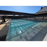 Lång rektangulär pooltime exklusiv pooltak med klar turkos vatten och svarta bärande balkar köpa pool
