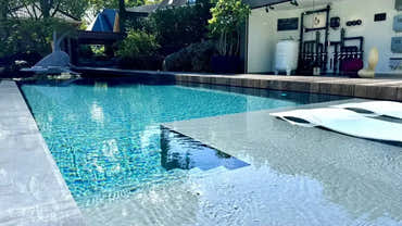 Pooltime exklusiv infinity med klart turkost vatten och svart kakel