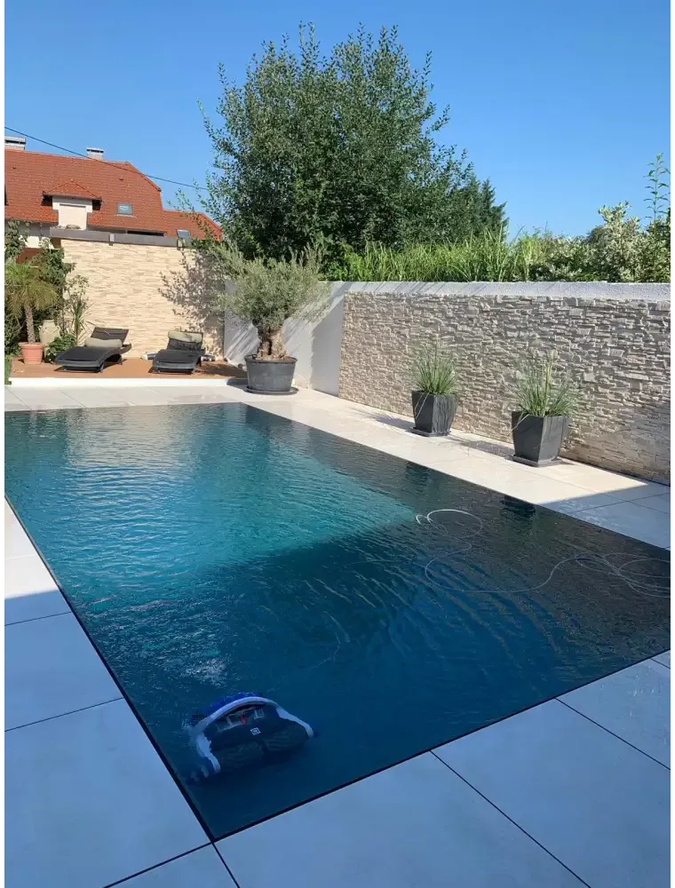 Blå och vit robotpoolrengörare i klart blått vatten i Pooltime Exklusiv overflow