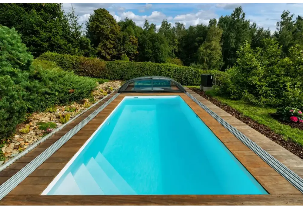 Rektangulär Thermopp Poolpaket Qbig med klart blått vatten, trädeck och grönska