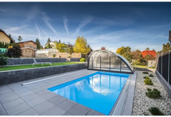 Blå rektangulär pool med genomskinlig valv och grå stenplattor i Thermopp Poolpaket Qbig