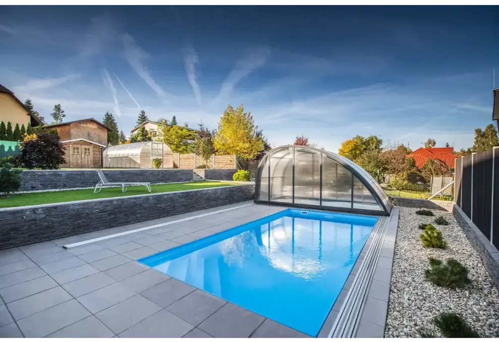 Blå rektangulär pool med genomskinlig valv och grå stenplattor i Thermopp Poolpaket Qbig